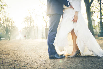 Low section of couple standing against trees