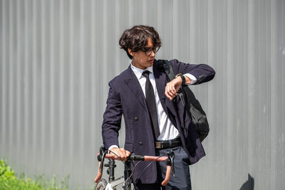 Side view of young man standing against wall