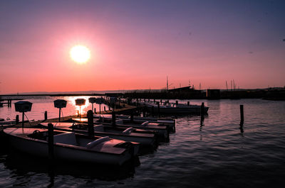 Boats moored in sea against clear sky at sunset