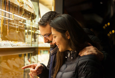 Smiling couple standing at jewelry shop at night
