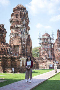 Full length portrait of smiling young woman standing in temple