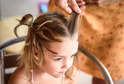 Cropped hands of mother tying daughter hair