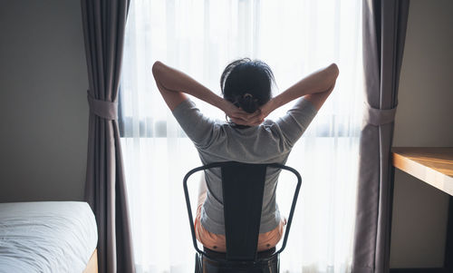 Rear view of woman relaxing on bed at home