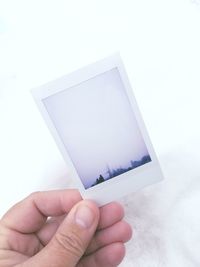 Close-up of hand holding snow over white background