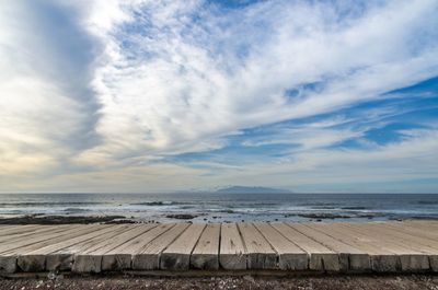 Boardwalk against the distant gomera island from the shore at playa de las americas in tenerife