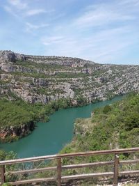 Scenic view of river by mountains against sky