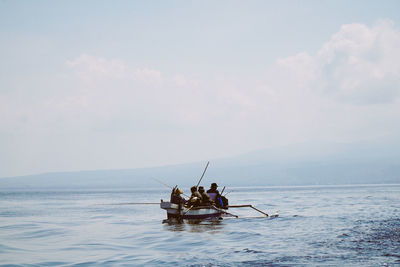 People in boat on sea against sky