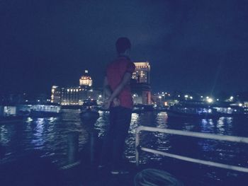 Rear view of man looking at illuminated city at night