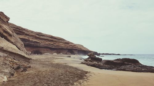 Rock formation on beach against sky