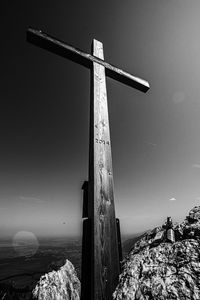 Cross on rock against sky