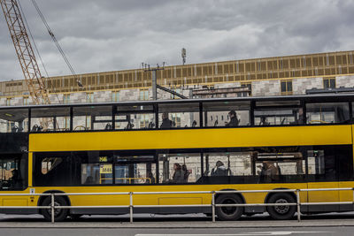 People in yellow bus on street by construction site