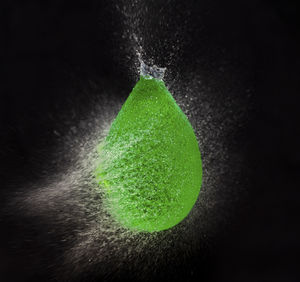 Close-up of green leaf on water against black background