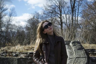 Portrait of young woman standing against bare trees