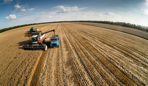 Agricultural vehicles and machinery on field against sky