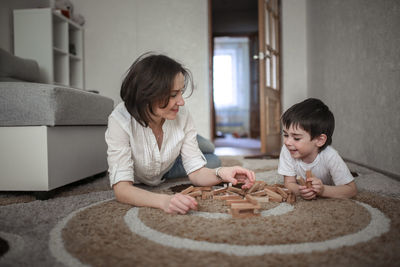 Happy family. mother and son playing in wooden designer and smiling. little boy having fun with 