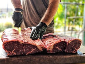 Midsection of man cutting meat on table in butcher shop