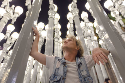 Low angle view of man standing amidst illuminated decoration