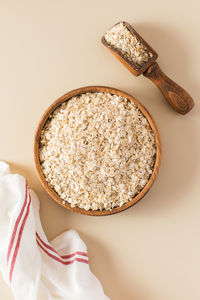 Oat flakes in a wooden bowl on a beige background. healthy eating.