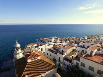 Lighthouse of peniscola and residential district by sea against sky