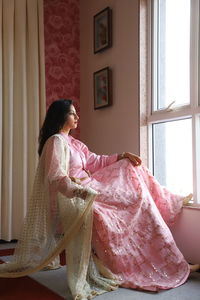 Woman looking through window at home