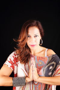 Portrait of smiling young woman against black background