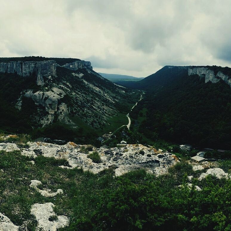 mountain, sky, cloud - sky, tranquil scene, scenics, tranquility, rock - object, cloudy, rock formation, nature, landscape, beauty in nature, mountain range, cloud, tree, built structure, non-urban scene, day, rocky mountains, hill