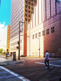 Rear view of man walking on footpath by buildings