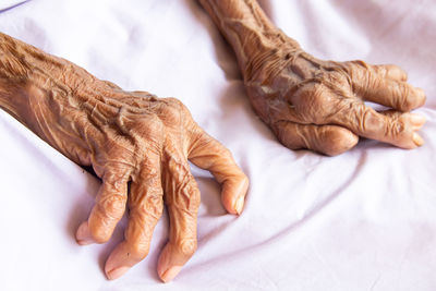 Cropped image of woman hand on bed