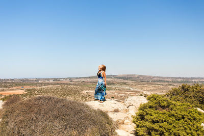 Young woman standing on land against clear sky
