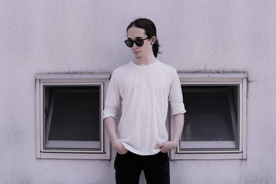 Portrait of young man standing against wall