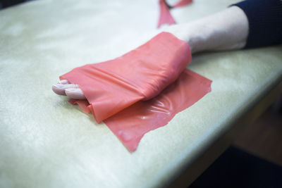 Cropped hand of patient wrapped in red adhesive bandage on hospital bed