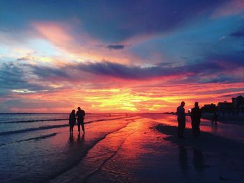 Silhouette men on beach against sky during sunset