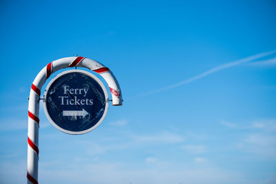 Low angle view of signboard against clear blue sky