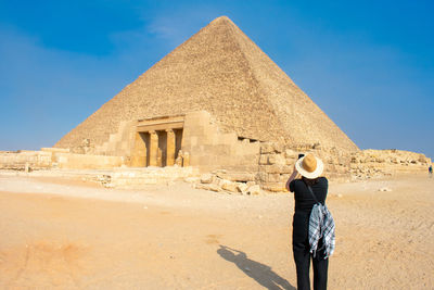 Rear view of woman walking at beach against clear sky