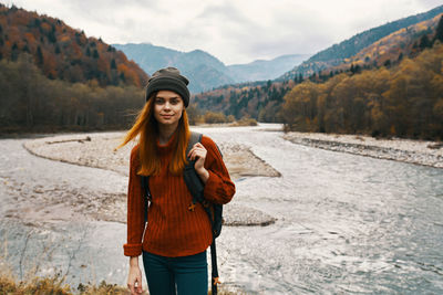 Portrait of smiling young woman standing against mountains