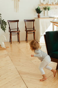 Rear view of girl playing with toy on hardwood floor at home