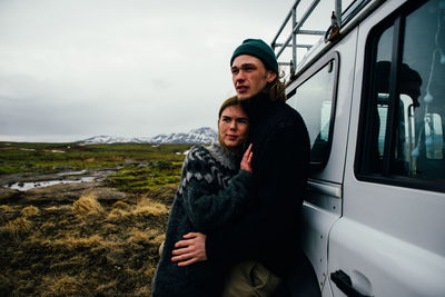 Young couple standing on road against sky