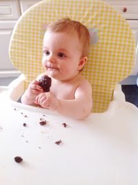 Baby boy eating food while sitting on high chair