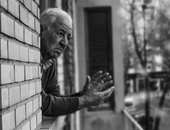 Thoughtful senior man looking through window