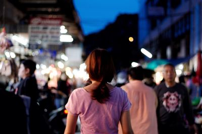 Rear view of people walking on city street at night