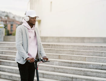 Man wearing hat standing on staircase in city