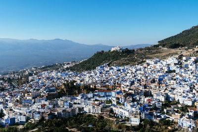 Aerial view of townscape and mountains against clear blue sky