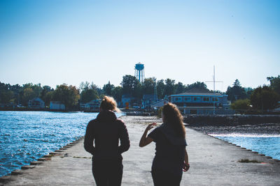 Rear view of friends on river against clear sky