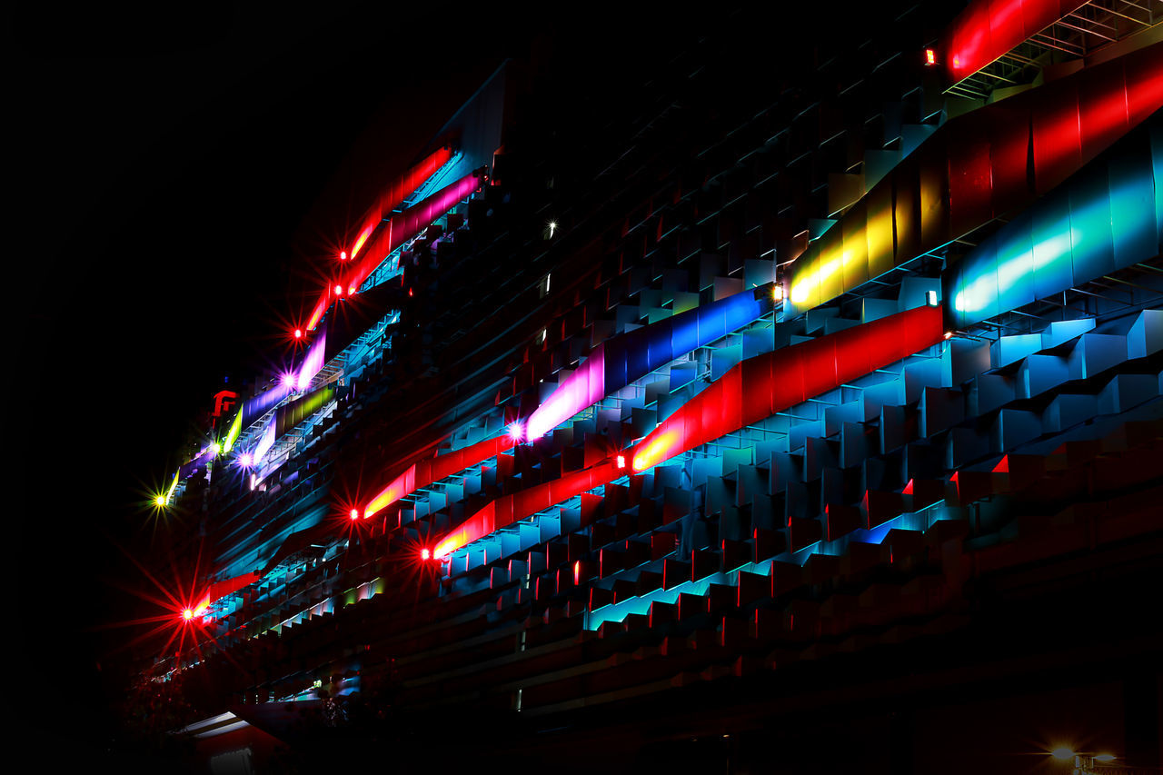 LOW ANGLE VIEW OF ILLUMINATED MODERN BUILDING AT NIGHT