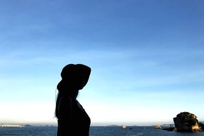 Silhouette woman standing at beach against sky