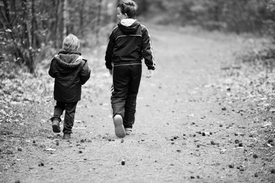 Rear view of boy walking with mother