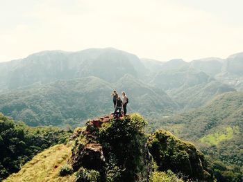 Friends standing on cliff against clear sky