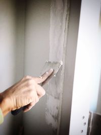 Cropped hand plastering wall at home