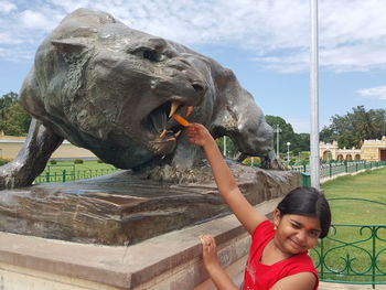 Portrait of girl holding popsicle in statue mouth