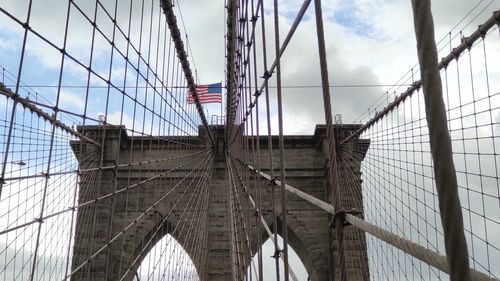 Low angle view of suspension bridge against cloudy sky